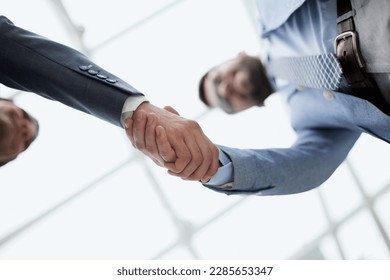 Business partners shaking hands in meeting hall bottom view