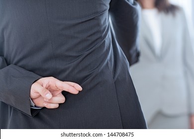 Business Partners Shaking Hands With One Of Them Holding Her Fingers Crossed Behind Her Back.