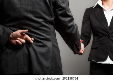 Business Partners Shaking Hands With One Of Them Holding Fingers Crossed Behind Back.