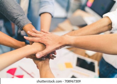 Business partners teamwork or friendship concept. Multi-ethnic diverse group of colleagues join hands together. Creative team, coworkers, or college students in project meeting at modern office