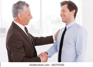 Business Partners. Two Cheerful Business Men Shaking Hands And Looking At Each Other