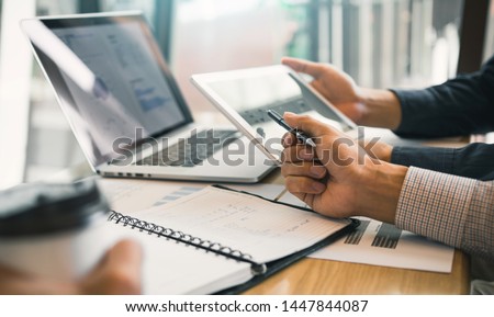 Business partnership coworkers using a tablet to chart company financial statements report and profits work progress and planning in office room.