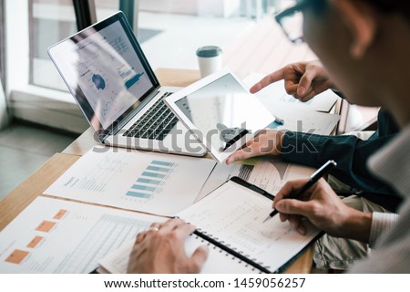 Business partnership coworkers using a tablet to analysis graph company financial budget report and cost work progress and planning for future in office room.