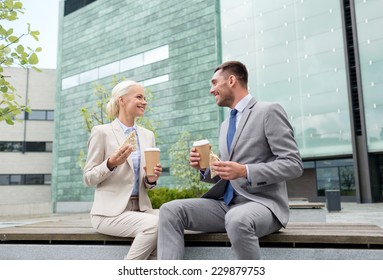 business, partnership, food, drinks and people concept - smiling businessmen with paper cups standing over office building - Powered by Shutterstock