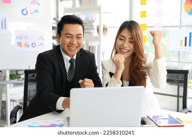 Business partnership meeting concept. Image of businessman cheer up with asian woman put their fist in the air as a successful teamwork in modern office. Successful businesspeople after good deal.  - Shutterstock ID 2258310241