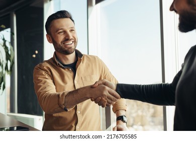 Business partnership. Smiling male entrepreneurs shaking hands, celebrating cooperation agreement at office. Two happy businessmen handshaking after successful deal at modern company - Powered by Shutterstock