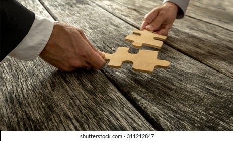 Business partnership or teamwork concept with a business people presenting a matching puzzle piece as they cooperate on finding an answer and solution, close up of their hands. - Shutterstock ID 311212847