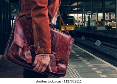 Business Passenger In Corduroy Brown Jacket With Real Leather Bag Waiting For The Train At Amsterdam Railway Station Platform