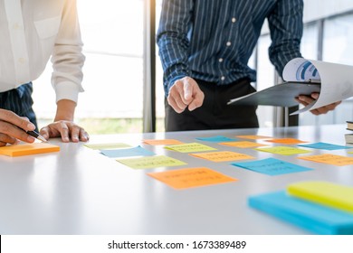 Business People Arranging Sticky Notes Commenting And Brainstorming On Work Priorities Colleague In A Modern Co-working Space