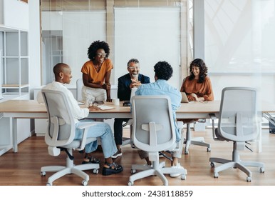 Business people in a boardroom engage in a productive discussion, collaborating on a project. Team members, both men and women, share ideas and plan together. A creative workplace environment. - Powered by Shutterstock