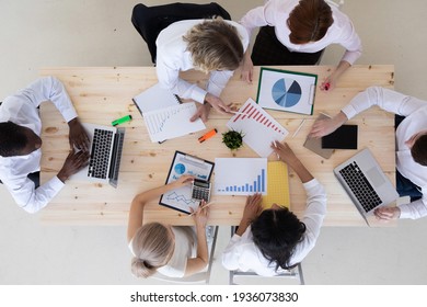 Geschäftsleute, die sich an einem Büroarbeitsplatz mit der Analyse von Finanzberichten und dem Hinweis auf Finanzdaten auf einer Tabelle, Draufsicht