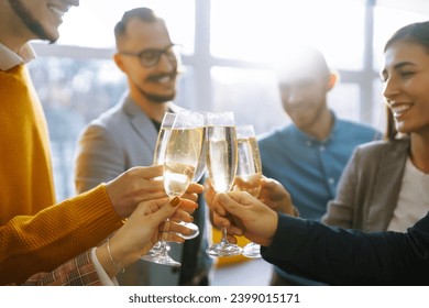 Business people celebrate with glasses of champagne in the office at a corporate event. A group of young people are having fun in the office. Holidays, business concept. - Powered by Shutterstock