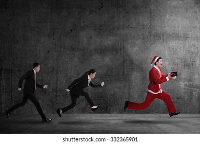 Business people chasing santa claus. Christmas bonus concept