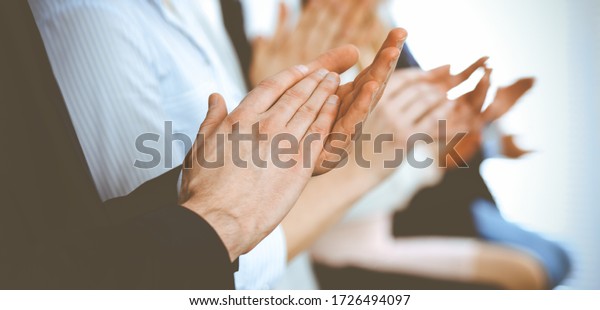 Business people clapping and applause at meeting\
or conference, close-up of hands. Group of unknown businessmen and\
women in modern white office. Success teamwork or corporate\
coaching concept