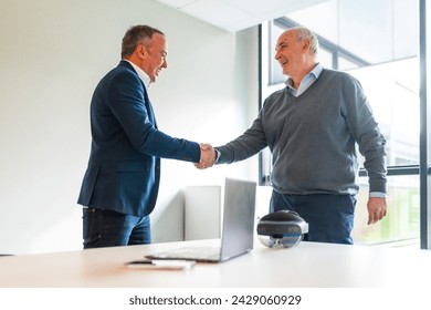 Business people closing a deal about an innovative mixed reality goggles handshaking in the office - Powered by Shutterstock