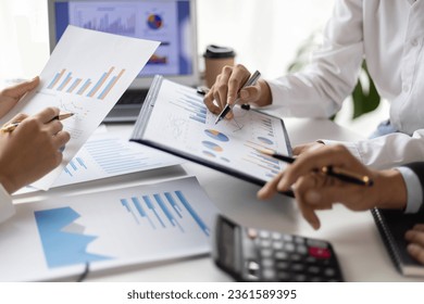 Business people and colleagues brainstorm together analyzing charts, financial reports and market growth graphs to plan new business investment strategies. Meeting to discuss statistical analysis. - Shutterstock ID 2361589395