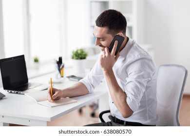 business, people, communication and technology concept - businessman calling on smartphone and writing to notebook at office