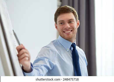 business and people concept - smiling businessman pointing marker to flipboard on presentation in office