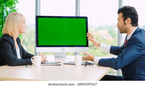 Business People In The Conference Room With Green Screen Chroma Key TV Or Computer On The Office Table. Diverse Group Of Businessman And Businesswoman In Meeting On Video Conference Call .