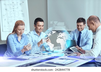 Business-, People-, Kooperations- und Technologiekonzept - lächelndes Geschäftsteam mit Gadgets und Hologramm-Treffen im Büro