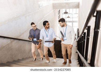 business, people and corporate concept - group of men with conference badges, folder, tablet pc computer and smartphone walking up office stairs - Shutterstock ID 2114227085