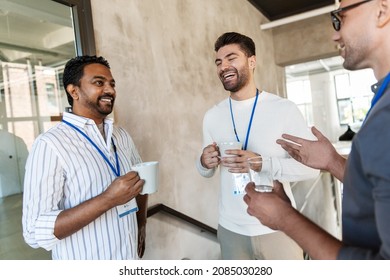 Business, People And Corporate Concept - Happy Smiling Businessmen Or Male Colleagues With Name Tags Drinking Takeaway Coffee At Office