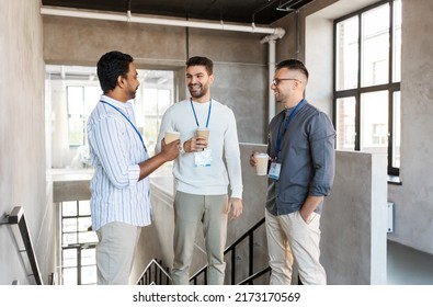 business, people and corporate concept - happy smiling businessmen or male colleagues with name tags drinking takeaway coffee at office