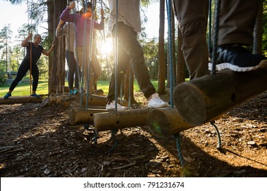 Business People Crossing Swinging Logs In Forest - Powered by Shutterstock