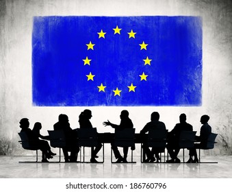 Business People Discussing Around The Conference Table And A Flag Of European Union 