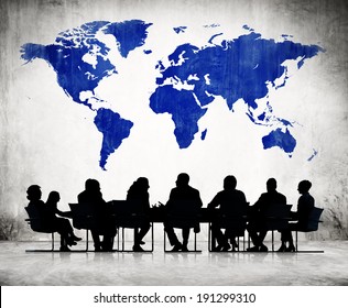 Business People Discussing Around The Conference Table And A Blue Cartography Of The World Above.