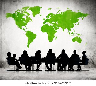 Business People Discussing Around The Conference Table And A Green Cartography Of The World Above