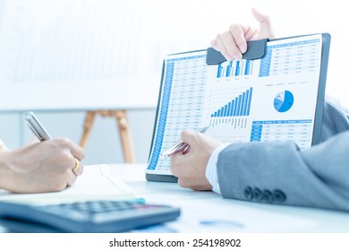 Business people discussing the charts and graphs showing the results of their successful teamwork - Shutterstock ID 254198902