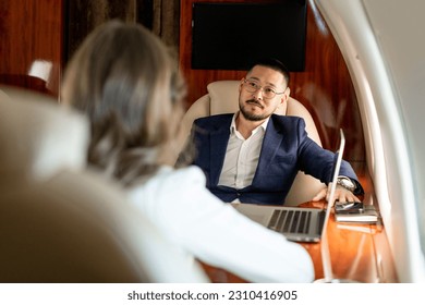 business people are discussing deal in private luxury jet, asian businessman in suit is talking to female colleague in airplane, korean boss is at meeting with client - Powered by Shutterstock