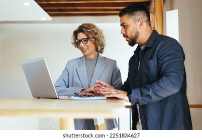 Business people discussing their work progress using a laptop in an office. Two business professionals working on a project together. Teamwork and collaboration between colleagues. - Powered by Shutterstock