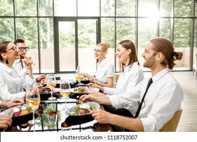 Business People Dressed In White Shirts Having Fun Sitting Together During A Business Lunch With Delicious Meals And Wine In The Modern Restaurant