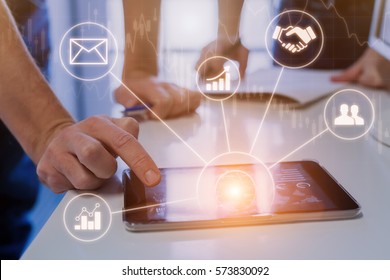 Business people during meeting in modern office using tablet computer for data and stock market analytics, icons and graph on virtual screen interface - Powered by Shutterstock