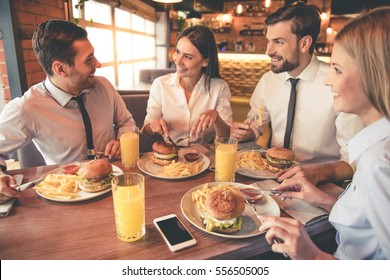 Business people are eating, talking and smiling while having lunch in cafe - Powered by Shutterstock