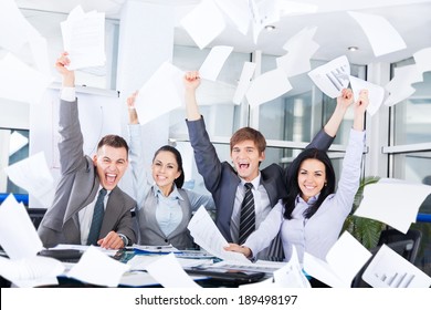 Business People Excited Happy Smile, Throw Papers, Documents Fly In Air, Businesspeople Sitting At Office Desk Hold Hands Arms Up, Success Team Concept After Sign Contract