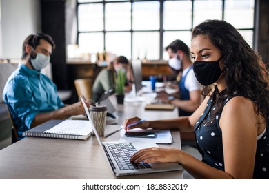 Business people with face masks indoors in office, back to work after coronavirus lockdown. - Shutterstock ID 1818832019