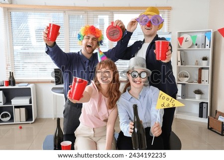 Business people in funny disguise with champagne celebrating April Fools' Day at office party