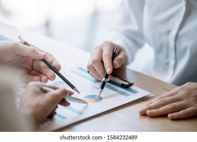 Business People Gather To Analyze Marketing And Investment Information And Using Pen Pointing To Financial Data Chart At Meeting.