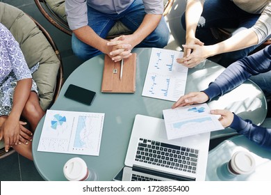 Business People Gathered At Office Table To Discuss Financial Charts And Diagrams At Meeting, View From Above