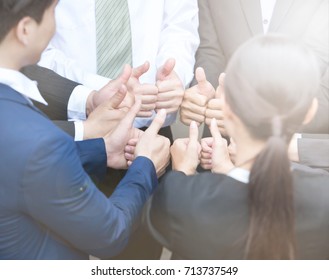 Business people give thumbs up sign
