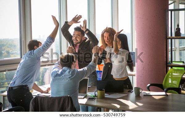 Business people giving five after dealing and\
signing contract or agreement with partners abroad. Colleagues\
showing team work in office\
interior.