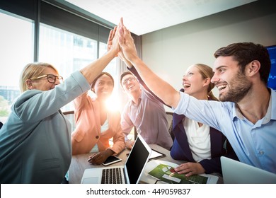 Business people giving high five at desk in the office