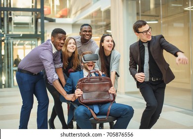 Business People Group At Modern Office Indoors Have Fun And Push Office Chair With Collegue Wearing Virtual Reality Headseton Corridor