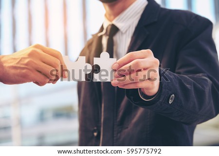 Business people Hand holding a jigsaw Puzzle assembly implementation to Assemble together. Representing the team and helping support confidence  Complement the team Together with of Business solutions