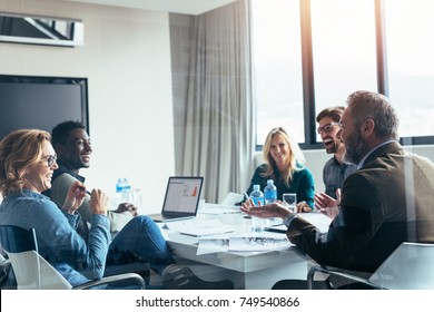 Business People Having Casual Discussion During Meeting In Board Room. Group Of Businesspeople Working Together.