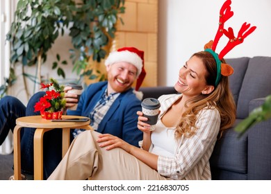 Business People Having Fun Celebrating Christmas At The Office, Wearing Costume Reindeer Antlers And Santa Hat, Taking A Coffee Break And Relaxing