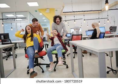 business people having fun while racing on office chairs